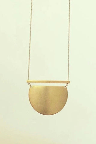 Foje necklace by Darlings of Denmark; raw brass; close-up shot; solid horizontal bar and a semi-circle solid pendant; flat lay