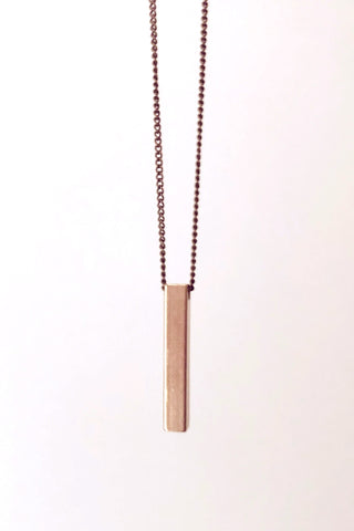 Gigi necklace by Darlings of Denmark; vertical solid bar detail; mid-length chain; close-up; raw brass; flat lay