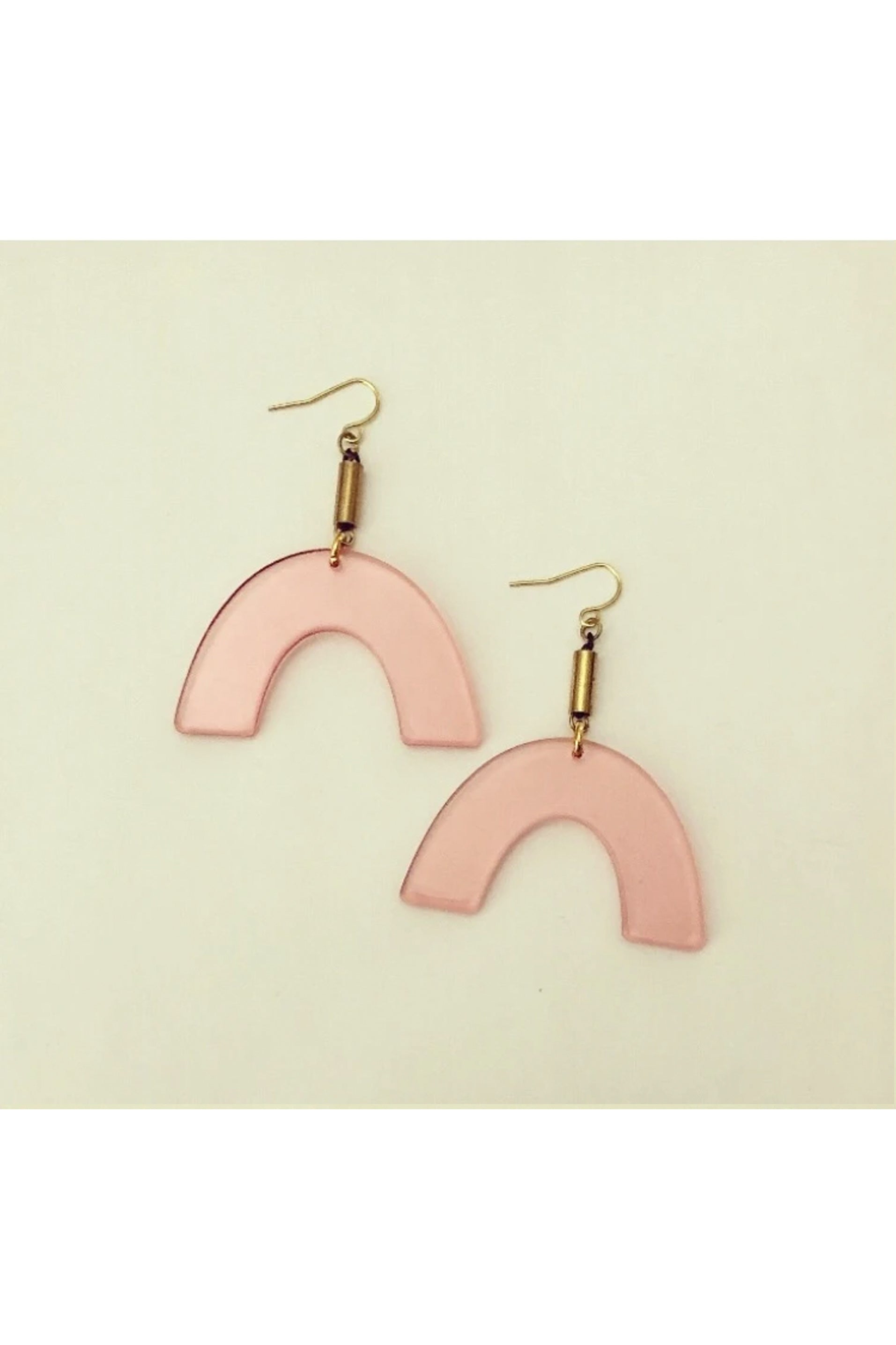 Vuttue dangle earring by Darlings of Denmark; semi-transparent pink acrylic arches hanging off raw brass tubes; flat lay